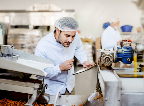 young-caucasian-serious-supervisor-evaluating-quality-food-food-plant-while-holding-tablet-man-is-dressed-white-uniform-having-hair-net 1